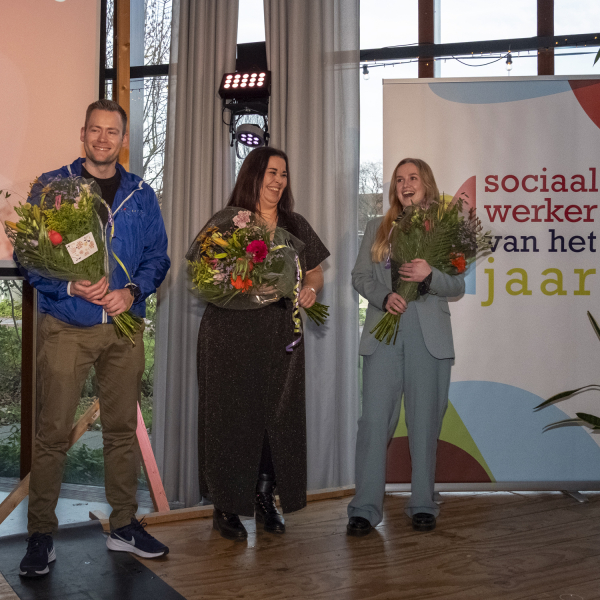 De drie genomineerden Michel, Kim en Jojanne met bloemen tijdens de uitreiking van Sociaal Werker van het Jaar 2025