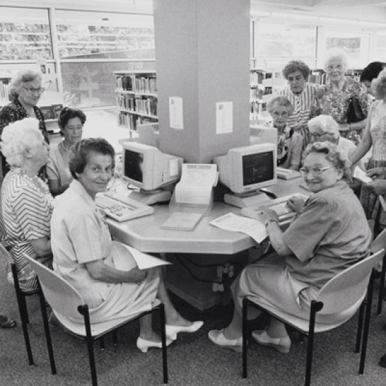 Foto uit expo van sociaal werkers die computerles geven aan ouderen