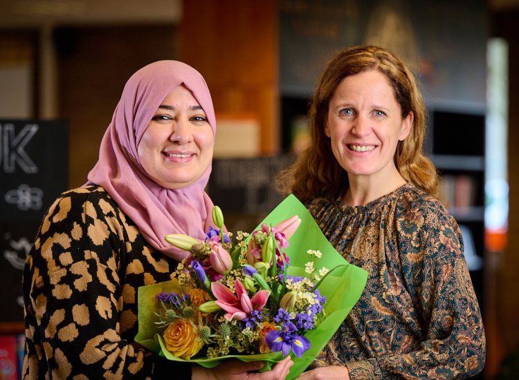 Yamina Ayada en Mirjam van Rijn kijken lachend in de camera met bos bloemen in de hand