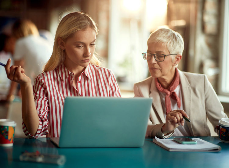 Jongere en oudere vrouw kijken samen naar een laptopscherm