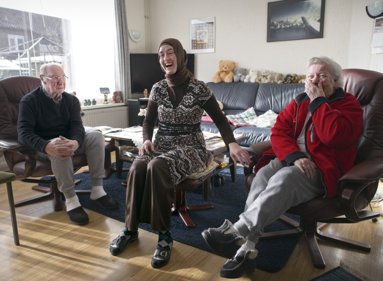 Foto van nu: sociaal werker lachend op de bank samen met cliënten
