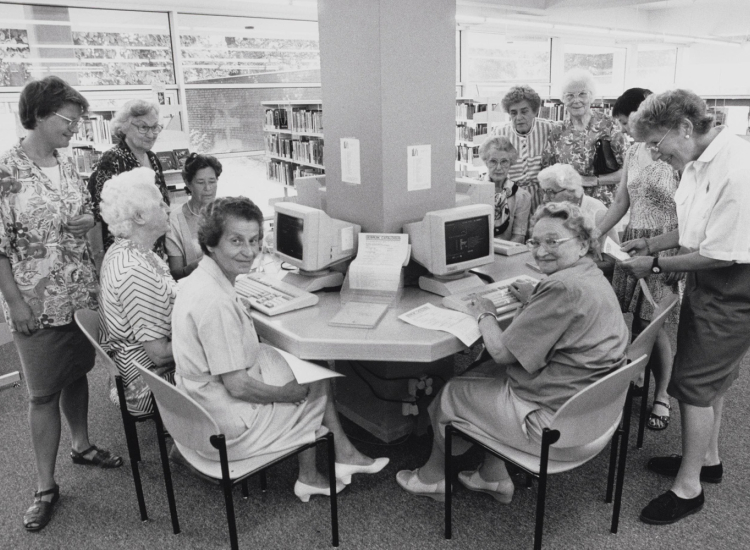 Foto uit expo van sociaal werkers die computerles geven aan ouderen